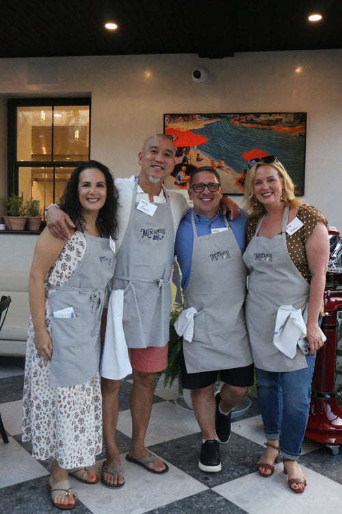 Four friends in Mercantile aprons smiling on the patio