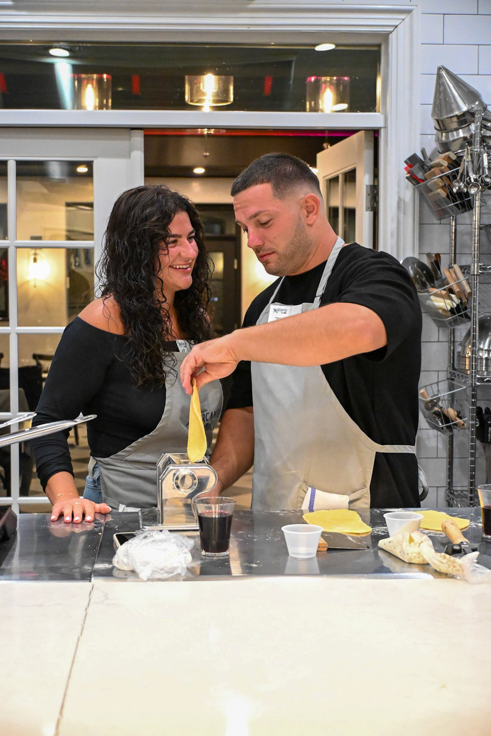 Two guests rolling fresh pasta through a pasta machine