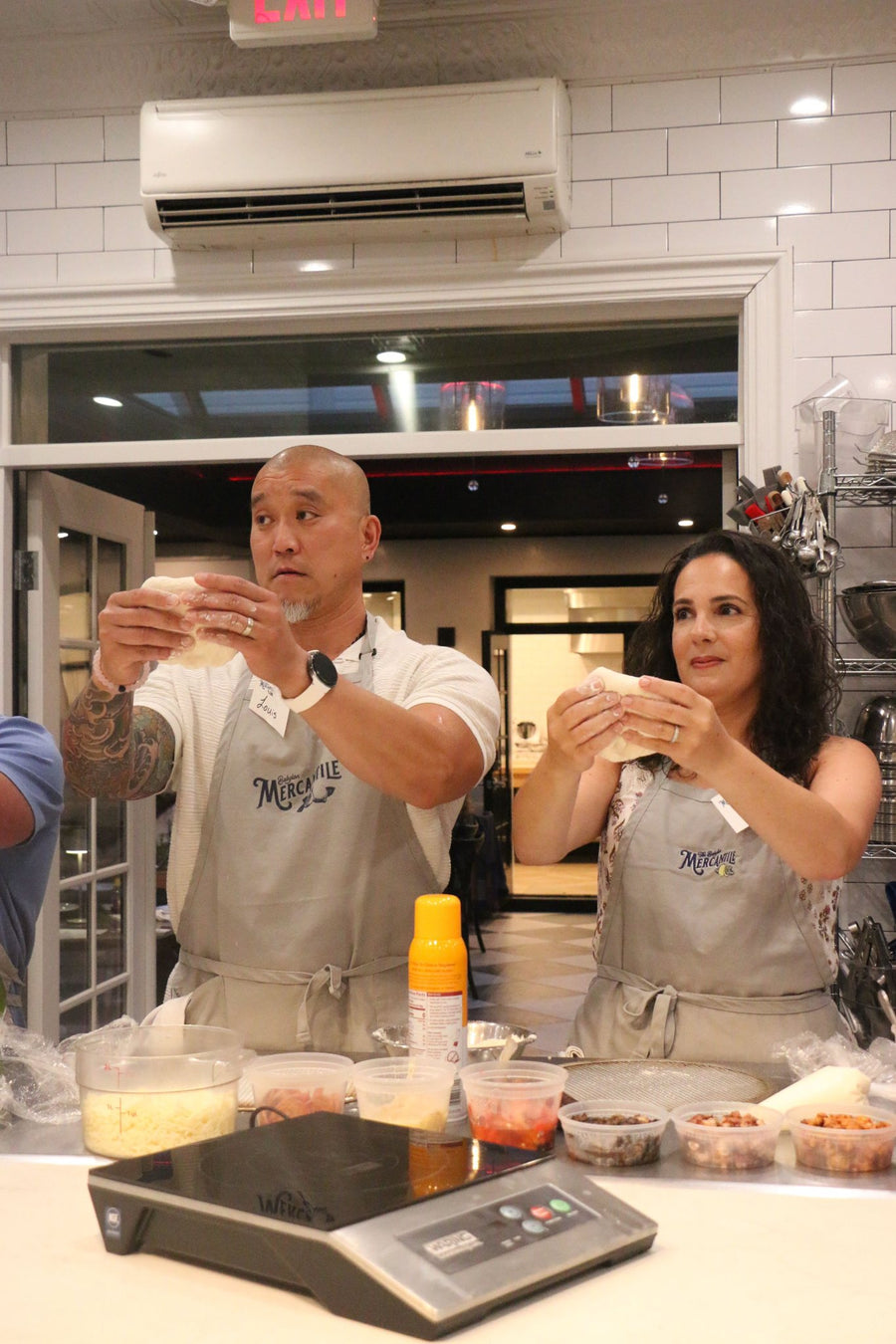 Guests stretching pizza dough in the Mercantile kitchen studio