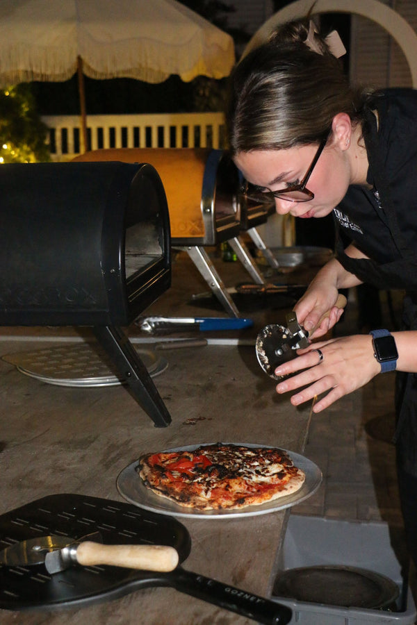 A Mercantile chef slicing a pizza fresh from the oven