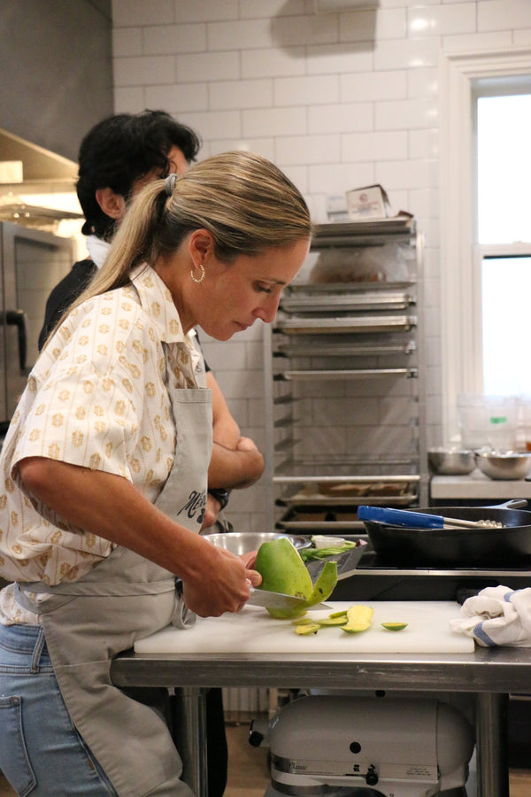A guest peeling a mango at a prep station